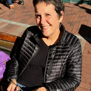 Nancy Canepa with short dark brown almost black hair, black scoop neck shirt, smiling.