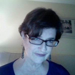A photograph of Darby Tench Leicht with short dark-brown almost black hair,  wearing glasses, blue shirt, smiling. 