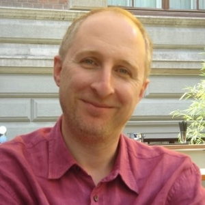 Marcello Simonetta smiling, wearing a burgundy cotton shirt on a sunny day