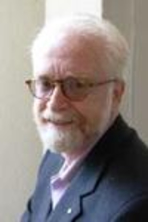 A photograph of Professor James Chiampi, wearing brown-rimmed glasses and a suit. 