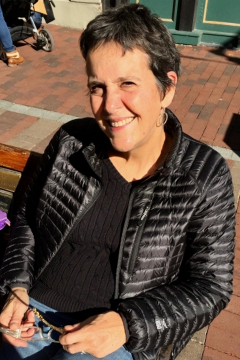Nancy Canepa with short dark brown almost black hair, black scoop neck shirt, smiling.