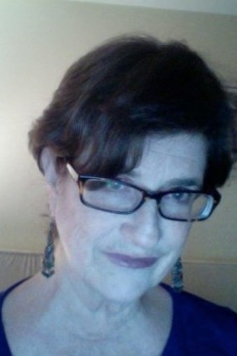 A photograph of Darby Tench Leicht with short dark-brown almost black hair,  wearing glasses, blue shirt, smiling. 
