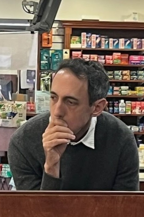 Christopher Kaiser leaning over with chin on hand wearing green sweater