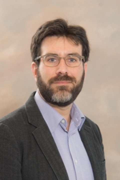 Daniel Leisawitz, fully bearded with glasses, lavender dress shirt and grey sports coat