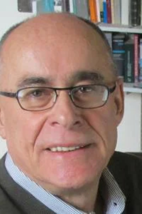 Massimo Lollini wearing glasses with book case in the background