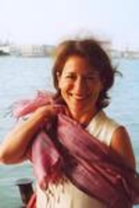 Margaret Rosenthal wearing a pink scarf with ocean in the background. She is smiling.