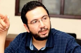 Belal Fadl sitting down speaking